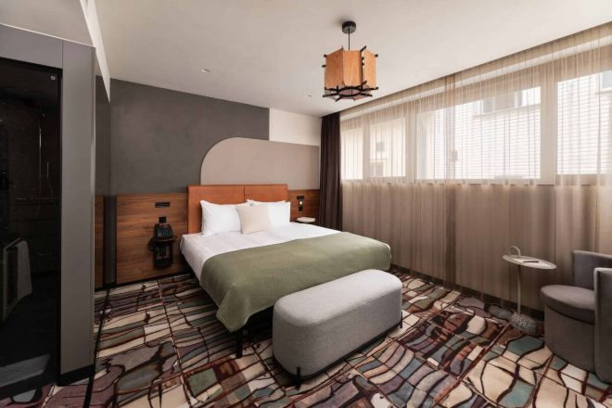A modern hotel room with a large bed, a small table, and a chair.