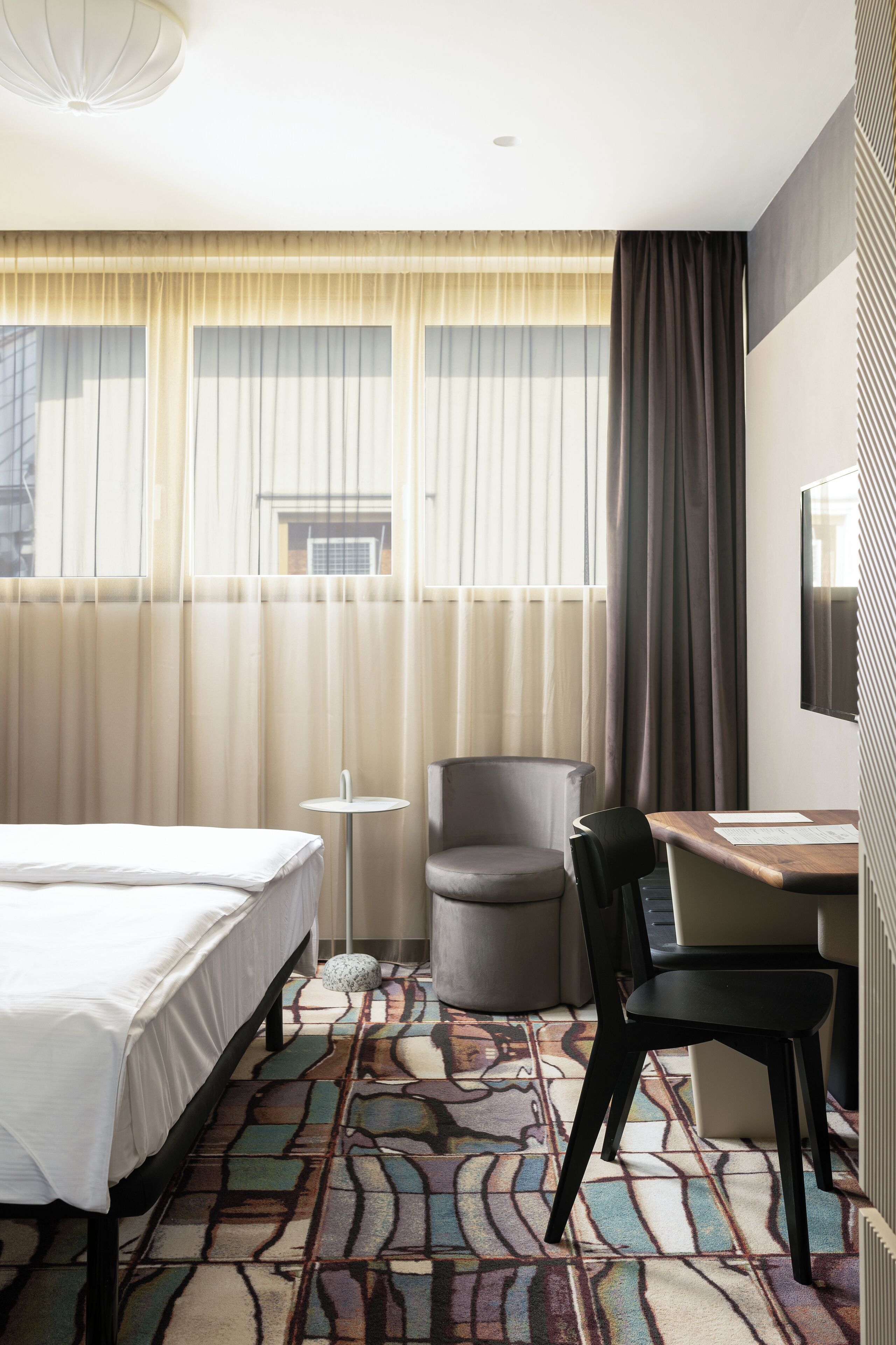 Una habitación de hotel con cama, escritorio, silla y televisor.