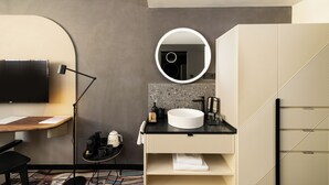 A modern bathroom with a round mirror, a sink, and a toilet. - Hotel GIN Budapest (Budapest)