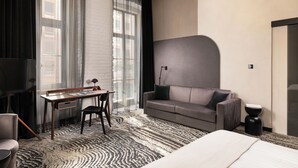 A modern hotel room with a large window, a sofa, a desk, and a bed. - Hotel GIN Budapest (Budapest)