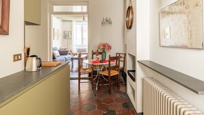 A kitchen with a coffee maker, a dining table with chairs, and a radiator. - Monti Charming Design Apartment (Roma)
