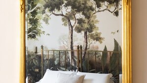 A bed with a headboard, a ceiling fan, and a wall-mounted mirror with a floral frame. - Monti Charming Design Apartment (Roma)