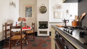 A modern kitchen with a gas stove, wooden chairs, a dining table, and a hanging mirror. - Monti Charming Design Apartment (Roma)