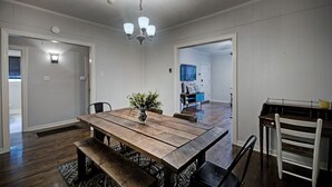 A dining area with a wooden table, benches, and chairs. There is a vase with flowers on the table. - Walk to Downtown Fondren | King Beds (Jackson)