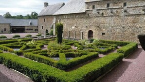 Een stenen gebouw met een formele tuin ervoor.