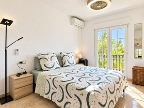 A bedroom with a bed, bedside table, lamp, and a view through a window. - Wonderful apartment with solarium terrace and community pools, Las Ramblas Golf (Orihuela Costa)