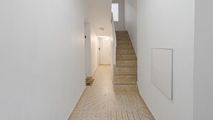 Ein schmaler Flur mit einer Holztreppe, die zu einer Tür am Ende führt.