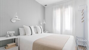 Ein ordentlich eingerichtetes Schlafzimmer mit einem Bett, Nachttischen und einem an der Wand befestigten Wäscheständer.