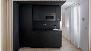Eine kleine Küche mit Mikrowelle, Backofen und Spüle, mit einem Fischgrätparkett und einem Streifenmuster an der Wand.