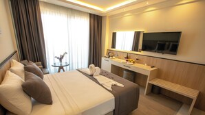 Quarto de hotel moderno com cama grande, mesa de cabeceira e televisão de tela plana na parede.