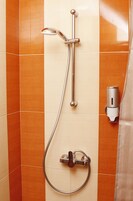 Een douche met een handdouche, een wandmengkraan en een bediening voor de handdouche.