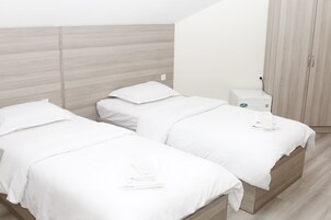 Een moderne hotelkamer met twee bedden, een garderobe en een klein nachtkastje.