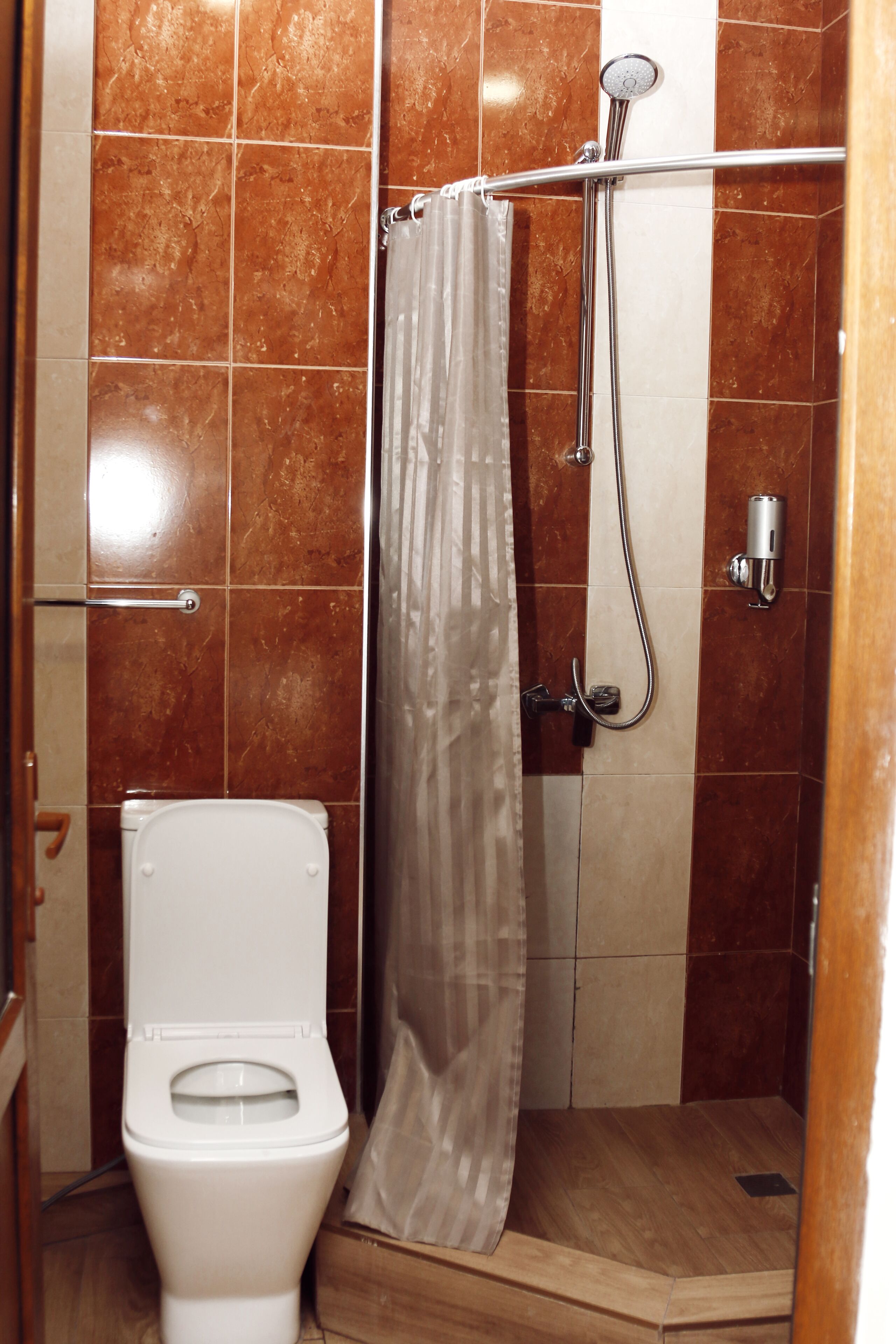 A bathroom with a shower, toilet, and a towel rack.