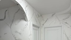 A hallway with marble-patterned walls, a wooden floor, and a door with a black handle. - Olive Hotel (Yerevan)
