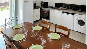 A kitchen with white cabinets, a stove, and a washing machine. - Maison du Périgord (La Douze)