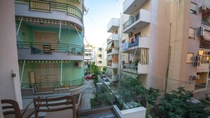A residential building with balconies, a small outdoor seating area, and a narrow street view. - Hotel Alion21 (Durrës)