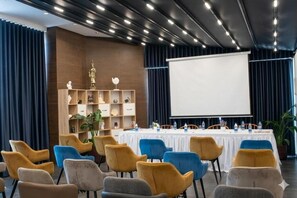 A conference room with a whiteboard, a projector screen, and a long table with chairs.