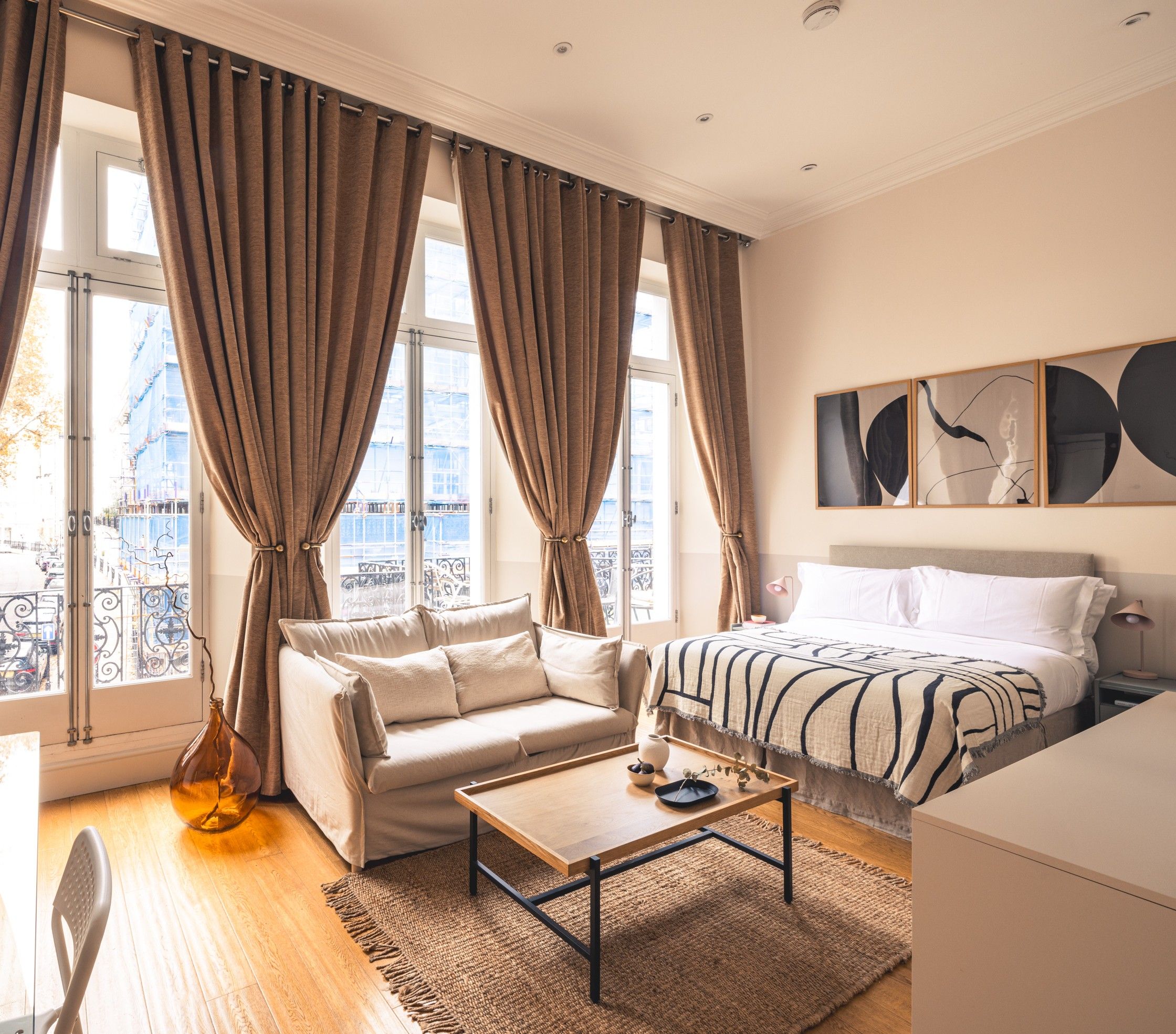 Una habitación de hotel con cama, sofá, una mesa de centro y vistas a la ciudad.