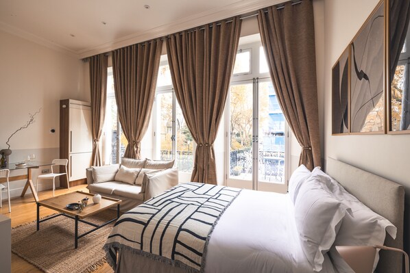 A hotel room with a bed, a sofa, a coffee table, and a desk.