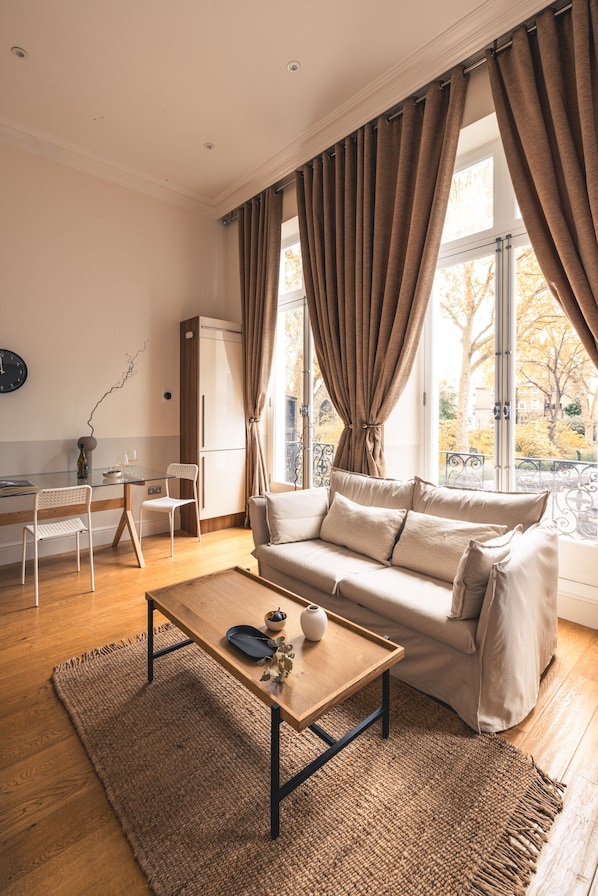A modern living room with a sofa, coffee table, and dining area. - The Courtfield by Nestor (London)