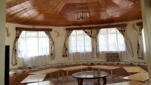 A room with a high wooden ceiling, multiple tables, and chairs arranged for dining or meetings. - Mataman Gardens (Naivasha)