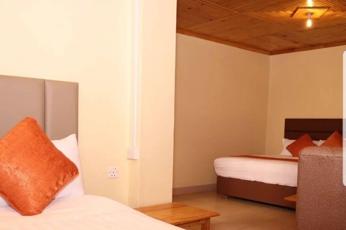 A hotel room with two beds, a wooden headboard, a small wooden table, and a chair.