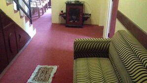Una sala de estar con un sofá, un televisor de pantalla plana en la pared, una escalera y un tapete estampado.