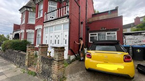 A red brick house with a white front door and a yellow car parked in front. - Lovely Flat Near Train Station and Central London (London)