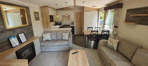 Un espacio habitable compacto con kitchenette, sofá, mesa de comedor y chimenea.