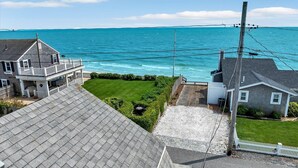 A coastal property with a view of the ocean, featuring a house with a balcony and a grassy yard. - Welcome To Tidal Fix! Classic Sea Side Cottage With Modern Comforts RPAM094 (Harwich)