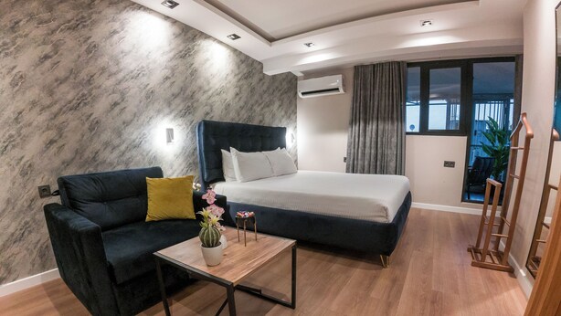 Ein modernes Hotelzimmer mit einem Bett, einer Couch, einem Couchtisch und einer Topfpflanze.