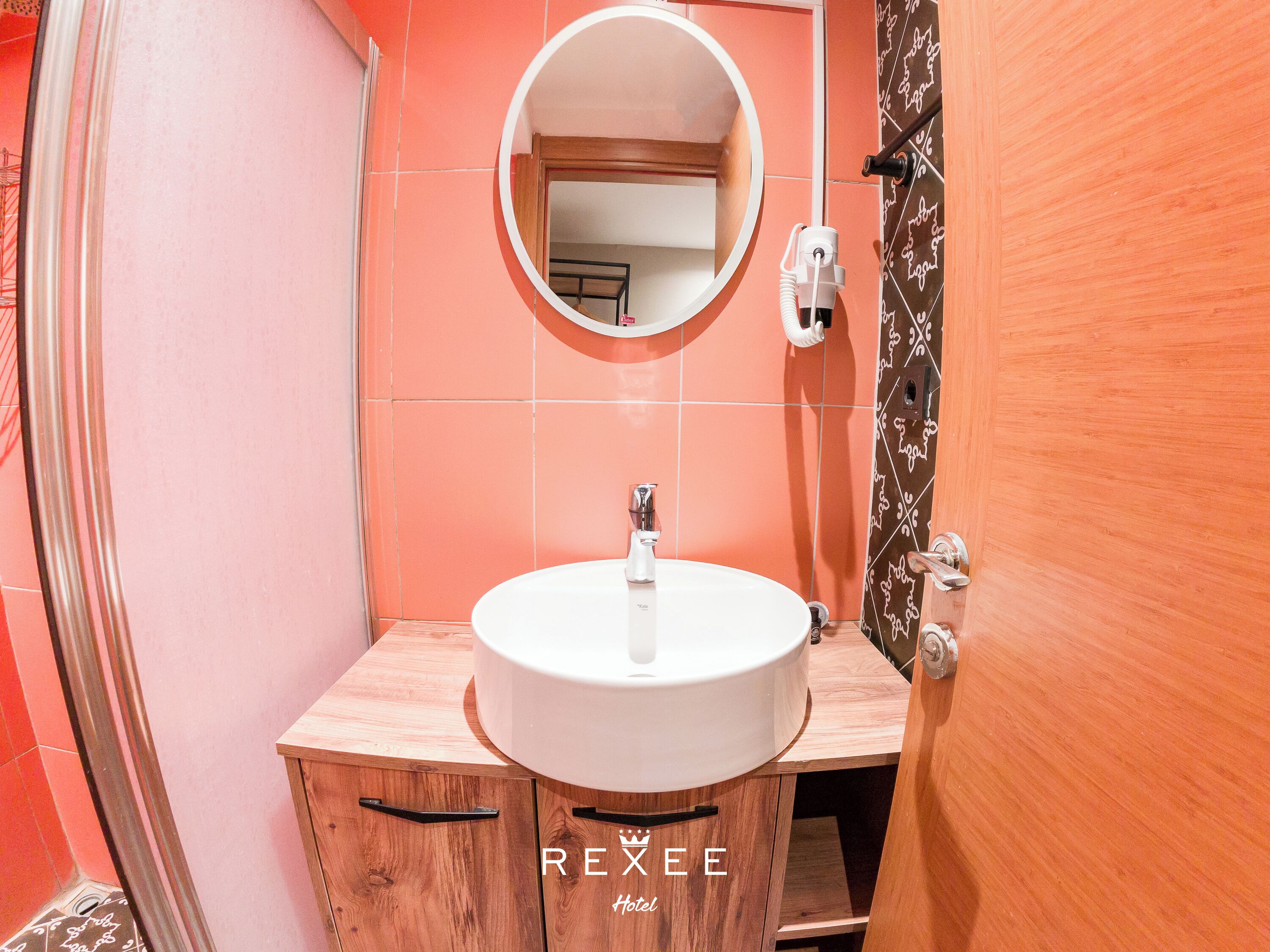 A bathroom with a round mirror, a white sink, and a wooden cabinet.