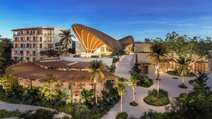 A resort with a large, uniquely shaped building, a pool area, and lush landscaping. - Secrets Playa Blanca Costa Mujeres - Adults Only - All Inclusive (Costa Mujeres)