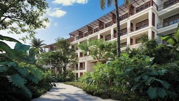 Un hotel de varios pisos con un jardín exuberante y un camino que lleva a la entrada.