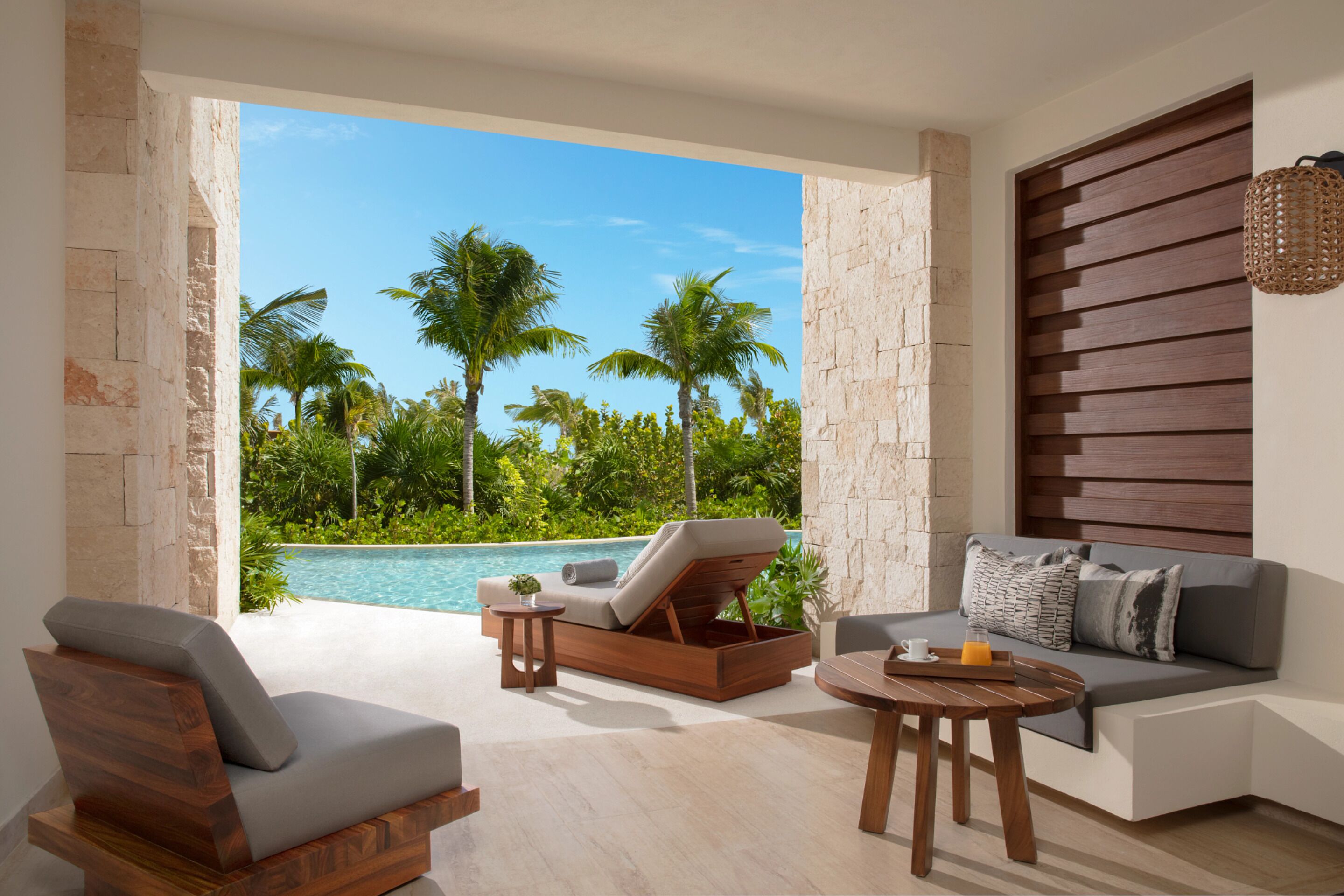 Un área de descanso moderna con vista a la piscina, un sofá y una mesa de centro de madera.