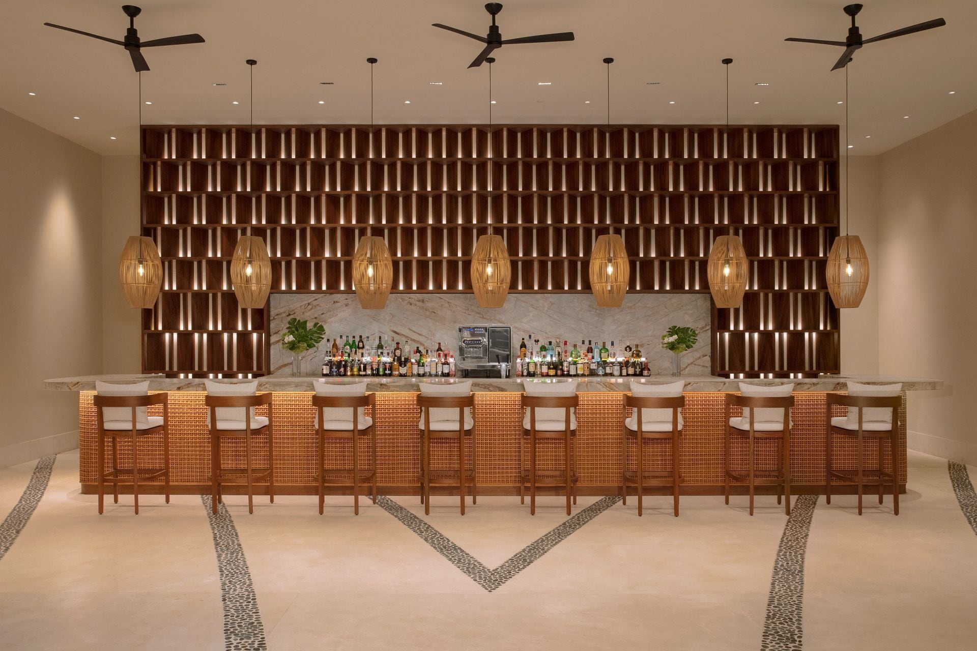 A bar area with a long counter, multiple seating options, and ceiling fans.
