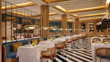 A restaurant with long tables, chairs, and a striped floor.