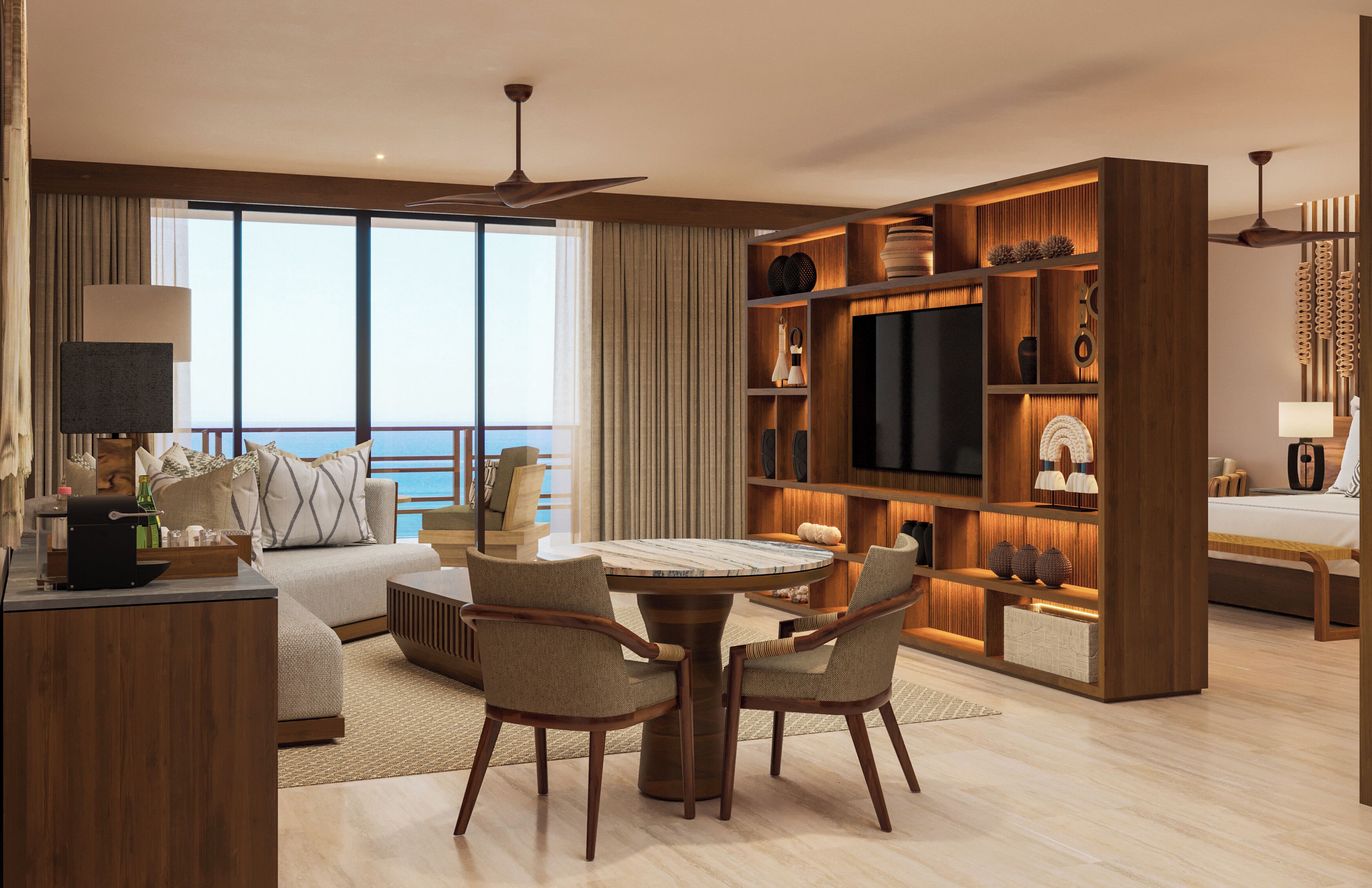 A modern hotel room with a large bed, a dining table, two chairs, a TV, and a bookshelf.