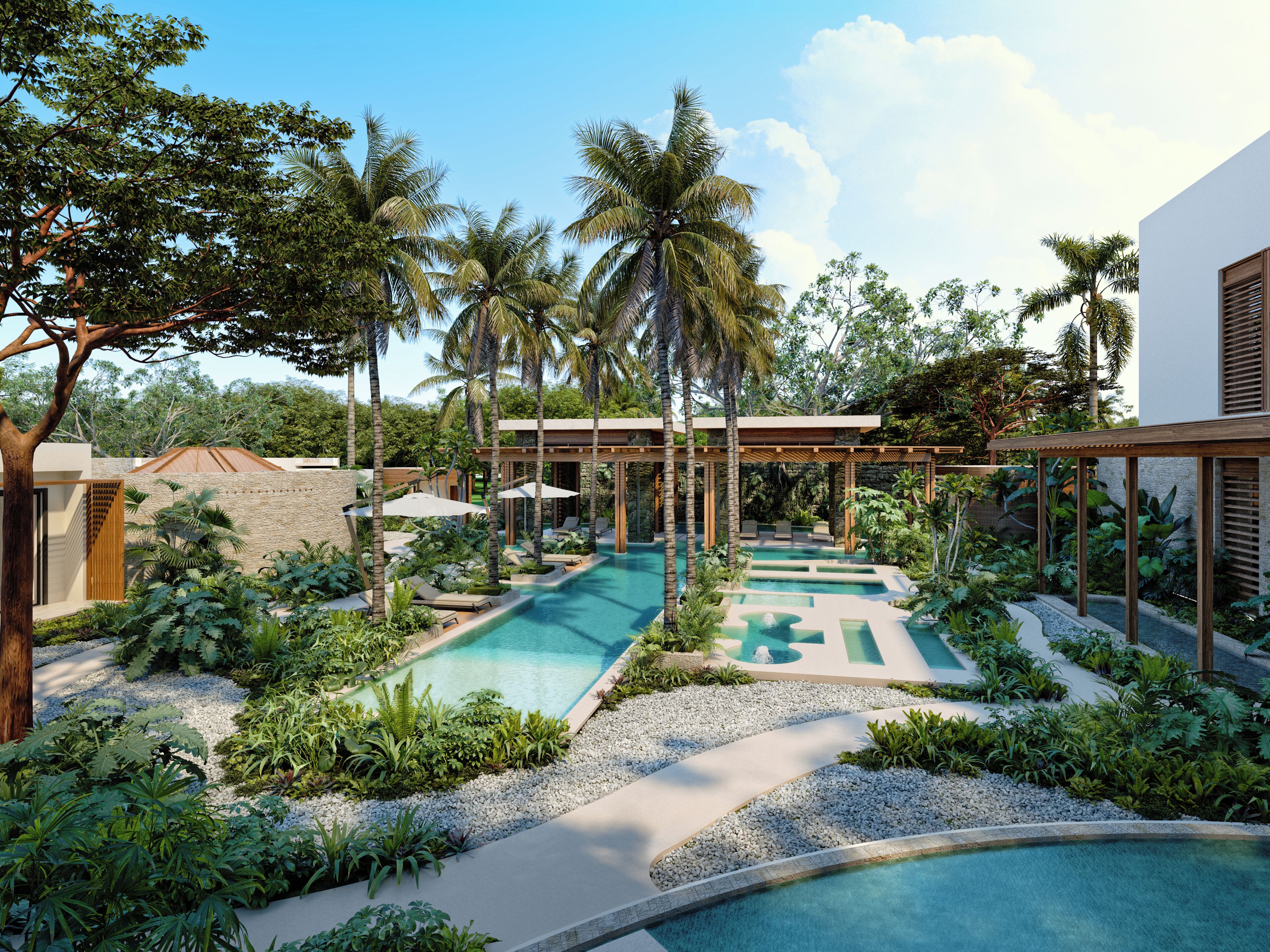 Un área de piscina con varias piscinas, rodeada de exuberante vegetación y palmeras.