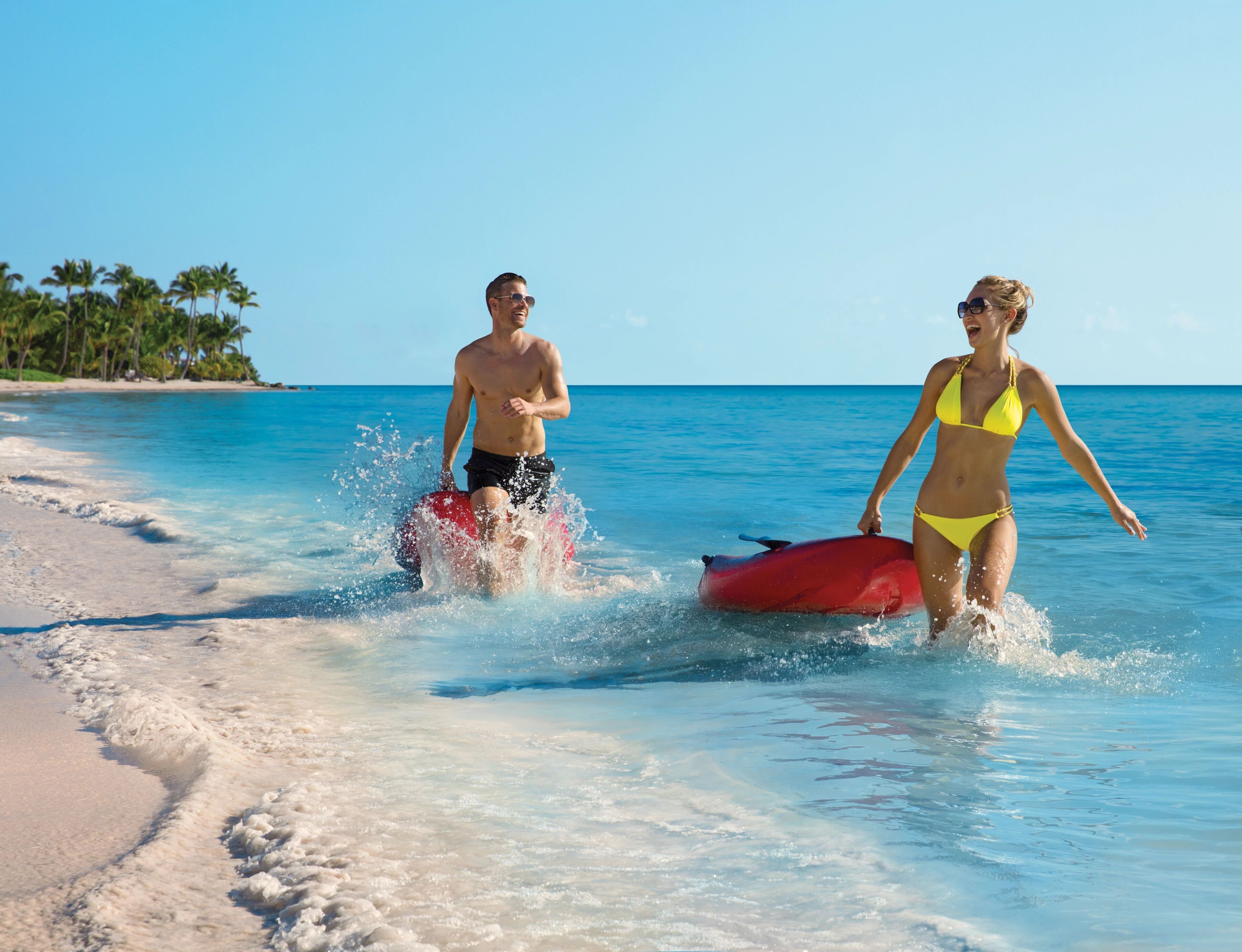 A beach scene with clear blue water and a sandy shore.