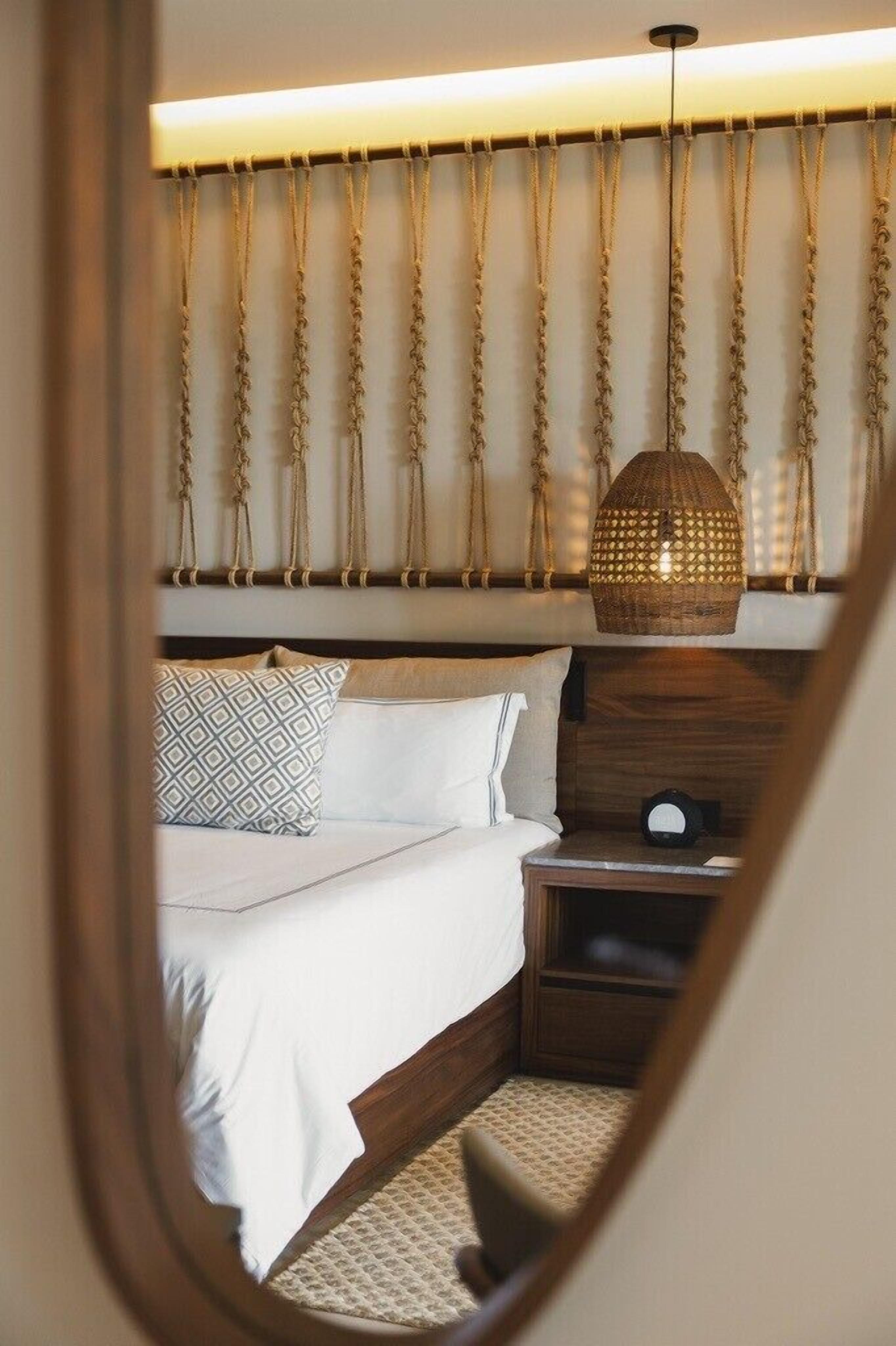 A bedroom with a bed, nightstand, and hanging light fixture.