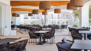 An outdoor dining area with wicker furniture and hanging wicker lamps.