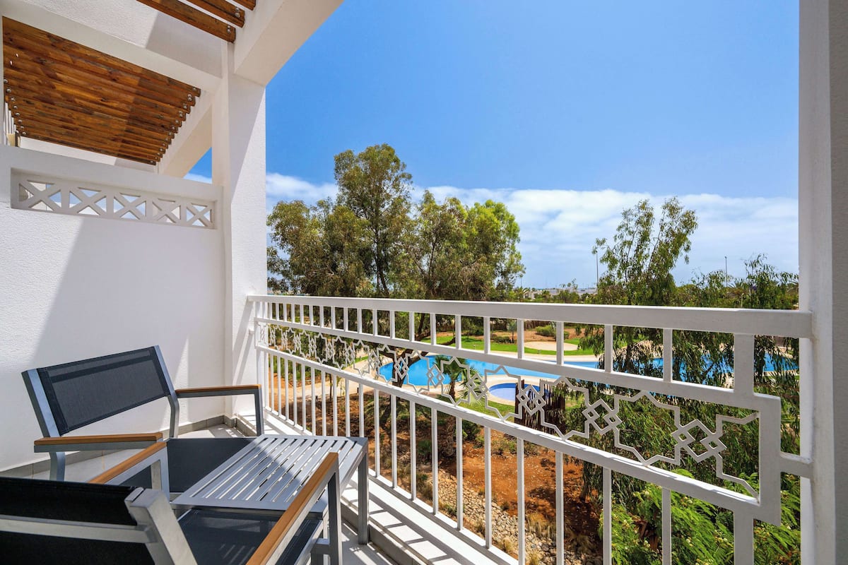 A balcony with a view of a pool and trees.