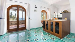 A room with a wooden cabinet, a tiled floor, and a view through a door. - Villa Nannina (Positano)