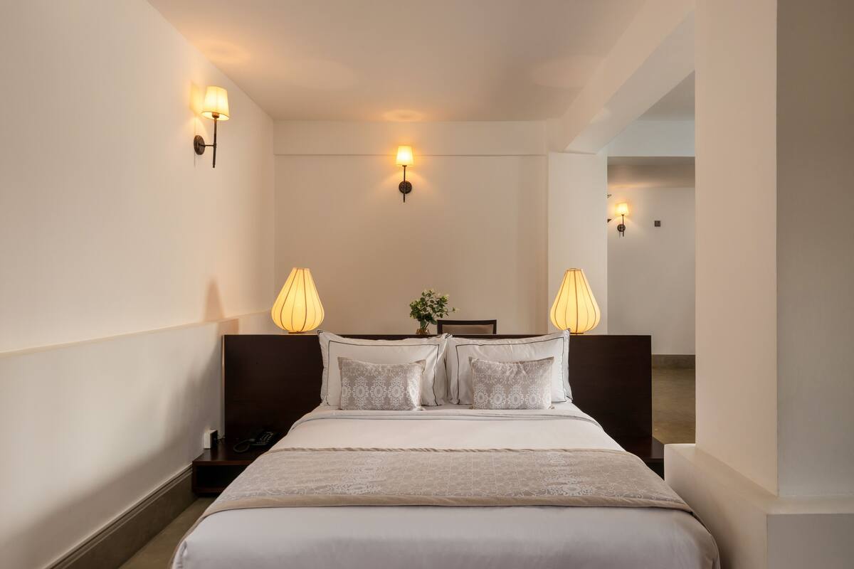 Ein Hotelzimmer mit einem großen Bett, zwei Nachttischlampen und einem Nachttisch mit Telefon.