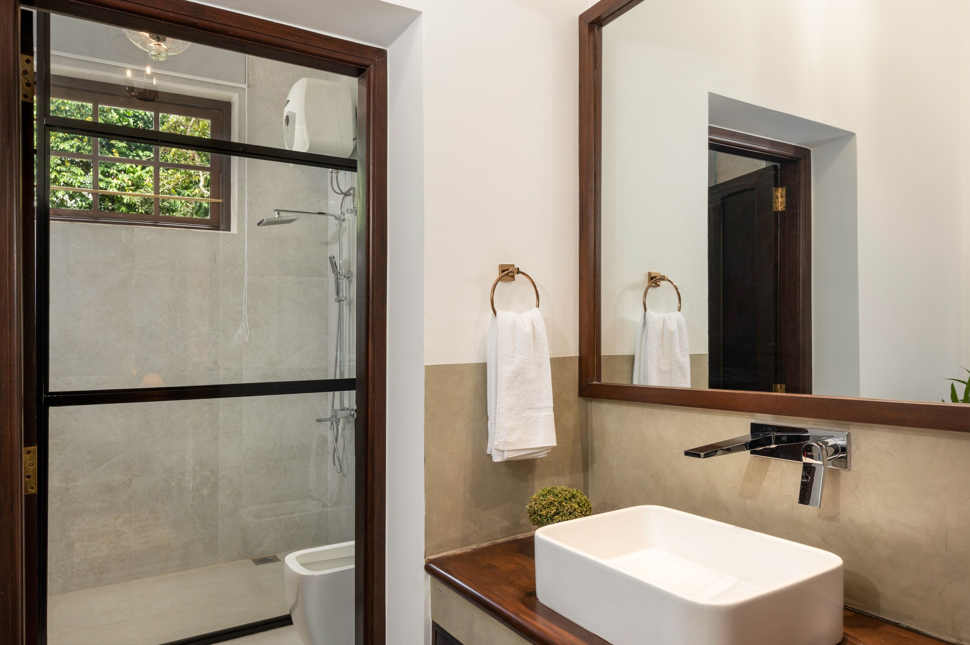 A modern bathroom with a glass shower enclosure, a white sink, and a large mirror.