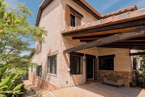 Uma casa de dois andares de tijolos com varanda coberta e parede de pedra.