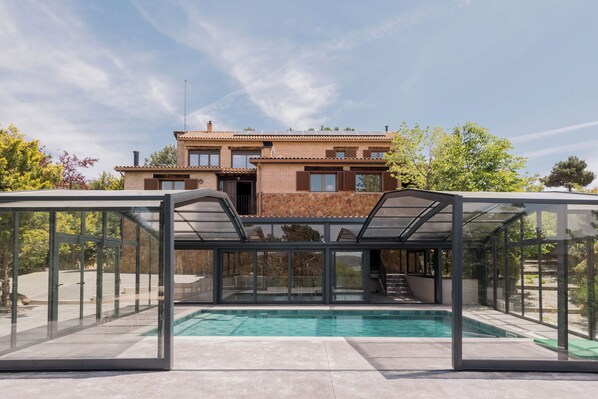 Uma casa moderna com piscina, varanda coberta e um grande jardim.