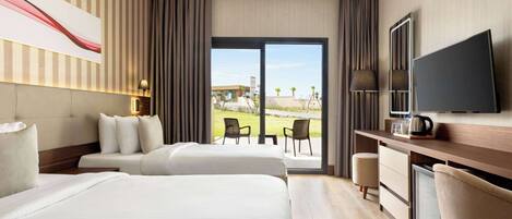 A hotel room with two beds, a desk with a TV, and a view of a courtyard.