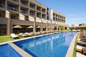 A hotel with a swimming pool, sun loungers, and umbrellas.